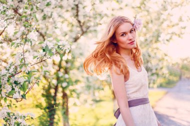 Çiçek açan elma ağacında poz veren kızıl saçlı bir model..