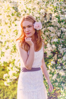 Çiçek açan elma ağacında poz veren kızıl saçlı bir model..