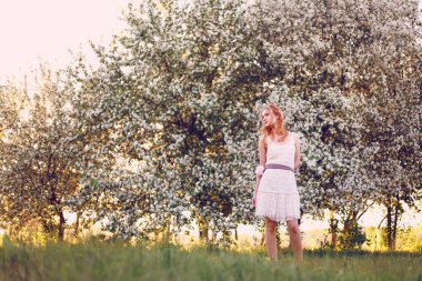 Çiçek açan elma ağacında poz veren kızıl saçlı bir model..