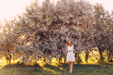 Çiçek açan elma ağacında poz veren kızıl saçlı bir model..