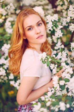 Çiçek açan elma ağacında poz veren kızıl saçlı bir model..