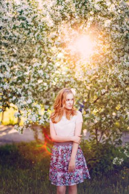 Çiçek açan elma ağacında poz veren kızıl saçlı bir model..