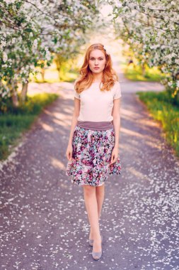 Çiçek açan elma ağacında poz veren kızıl saçlı bir model..