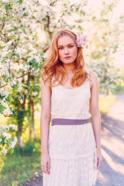 Çiçek açan elma ağacında poz veren kızıl saçlı bir model..