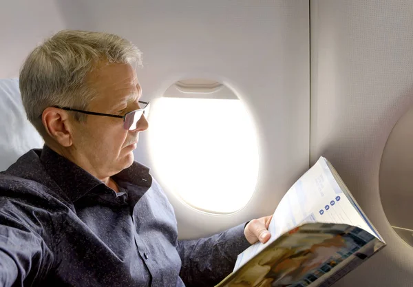 Mitt år kaukasiska mannen läser tidningen i flygplan — Stockfoto