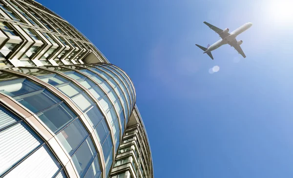 Flugzeug fliegt über modernem Bürogebäude. — Stockfoto