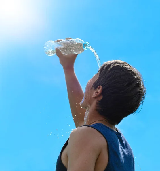 Giovane uomo spruzzando e versando acqua fresca da una bottiglia sulla testa — Foto Stock