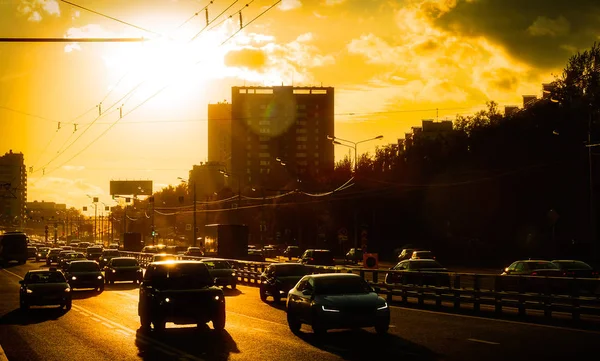 Carros se movendo na cidade ao pôr do sol contra o sol — Fotografia de Stock