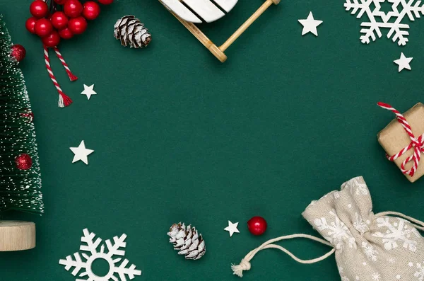 Neujahrs- und Weihnachtskomposition aus dekorativem Tannenbaum, Schlitten, Schneeflocken und Dekorationen auf grünem Hintergrund. — Stockfoto
