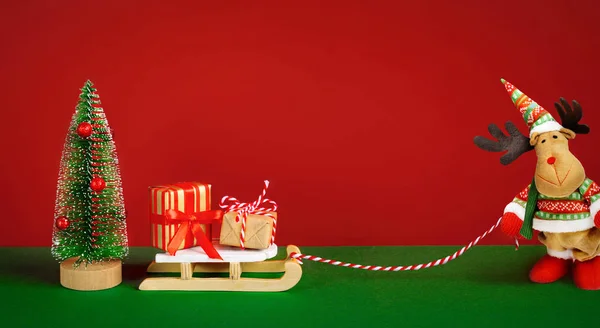 Χριστουγεννιάτικη σύνθεση με αστεία άλκη με δώρα στο έλκηθρο. Χριστουγεννιάτικη κάρτα. — Φωτογραφία Αρχείου