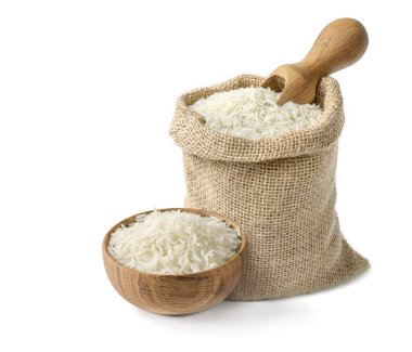 Beyaz arka planda tahtadan bir kase ve tahta kepçeli çuval içinde kuru, uzun pirinç basmati..
