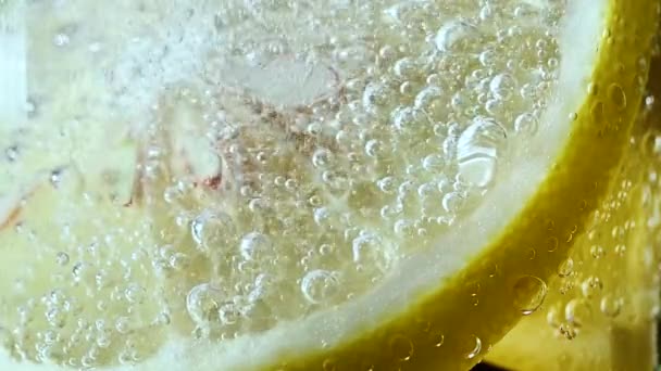 Rebanada de limón con burbujas en agua de soda con hielo — Vídeos de Stock