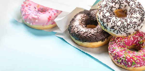 Verschiedene Donuts glasiert mit Streusel auf blauem Tisch. — Stockfoto
