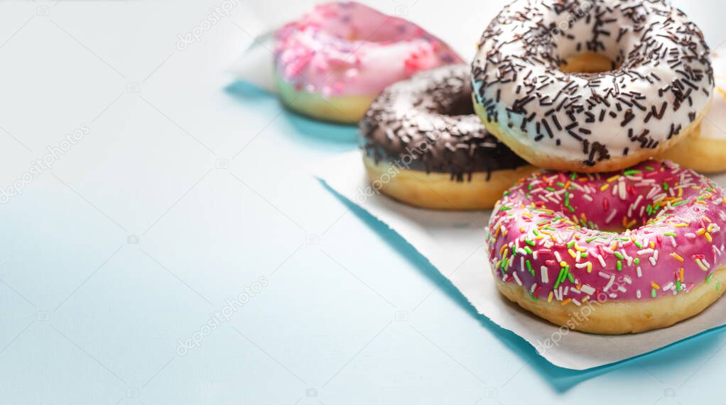Assorted dougnuts glazed with sprinkles on blue table.