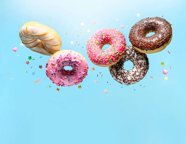 Fliegende Donuts. Mischung aus bunten Donuts mit Streusel auf blauem Hintergrund mit Kopierraum — Stockfoto