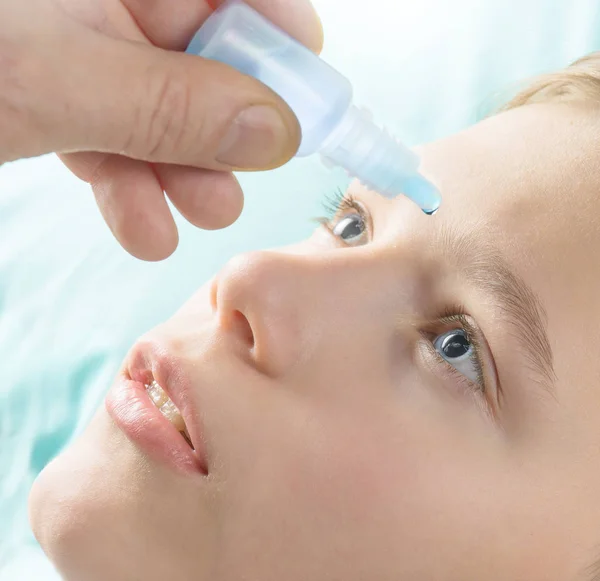 Teen boy dripping eye with eyes drops