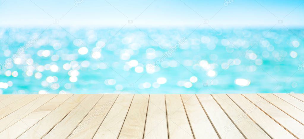 The blur sea and sky background with wood deck or table on the beach.