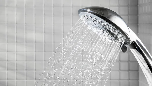 Cabeça de chuveiro com água corrente no banheiro branco — Fotografia de Stock