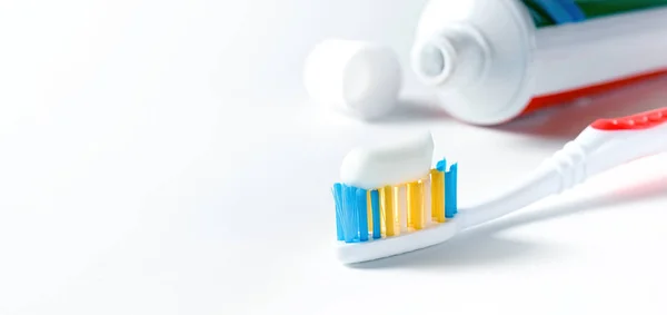 Toothbrush with white toothpaste and tube of toothpaste on white background — Stock Photo, Image
