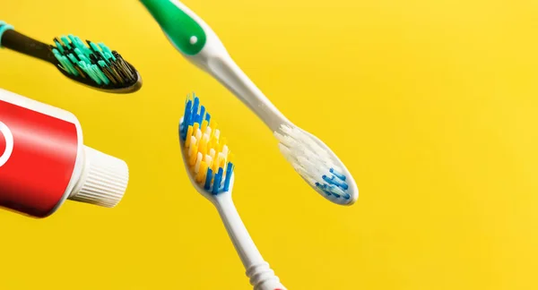 Toothbrushes and toothpaste tube over yellow background. Copy space. Selective focus. — Stock Photo, Image
