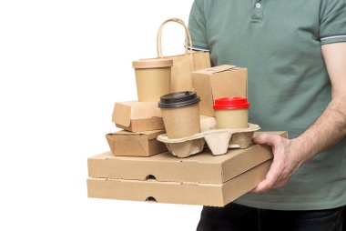 Paket teslimatçı elinde çeşitli yemek kutuları, pizza kutusu, kahve bardakları ve beyaz poşetlerle izole edilmiş kağıt poşetler tutuyor..