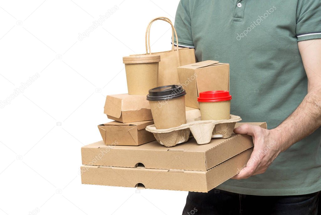 Delivery man holding various take-out food containers, pizza box, coffee cups in holder and paper bag isolated on white.