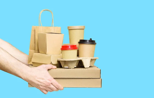 Mani che tengono assortimento di contenitori per la consegna di cibo isolati su sfondo blu. Servizio di consegna cibo — Foto Stock