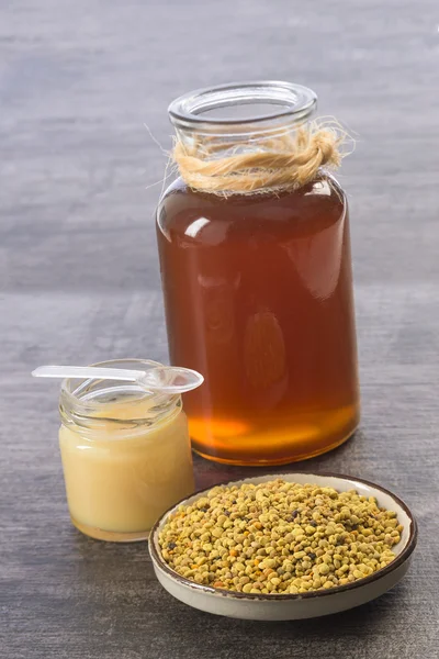 Golden bee pyłek iin kubek z royal jelly i miód w słoiku szkła — Zdjęcie stockowe