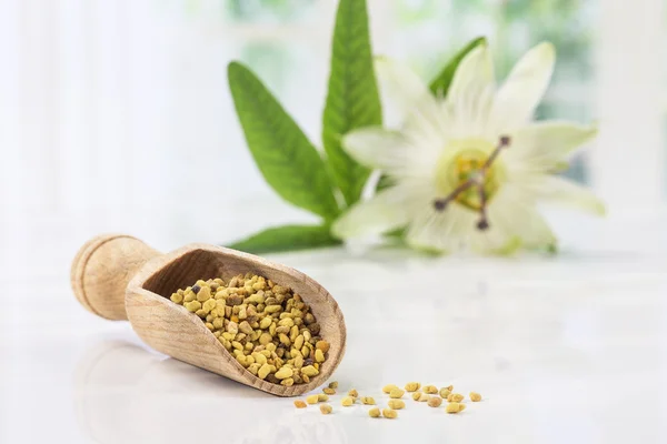 Polen de abeja en la cuchara en blanco con flor de pasiflora —  Fotos de Stock