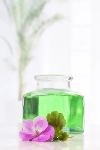 Ätherisches Geranienöl in Flasche und Blüten — Stockfoto