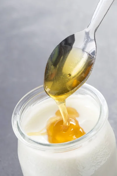 Iogurte e verter mel sobre fundo branco — Fotografia de Stock