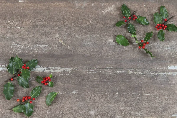Kerstmis achtergrond met Holly bladeren en bessen op een houten brown . — Stockfoto