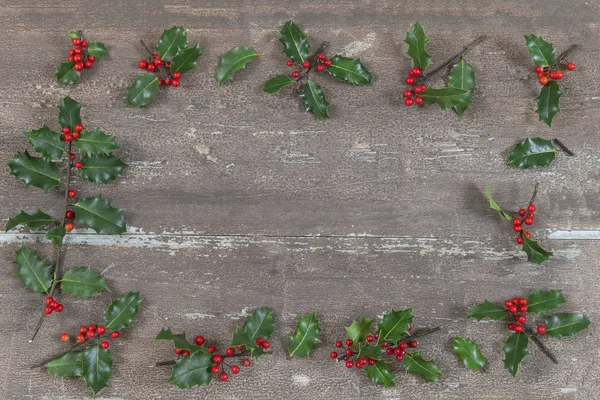 Kerstmis achtergrond met Holly bladeren en bessen op een houten brown . — Stockfoto