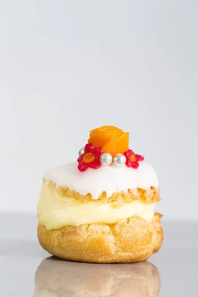 Torte di soffio alla panna o profiterole ripiene di panna montata servite con frutta e decorazione e fiore di glassa — Foto Stock