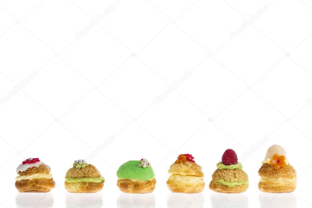 Cream puff cakes or profiterole filled with whipped cream with fruit and decoration in line