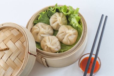 Buğulanmış domuz buns Asya dim sum bambu sepet, yemek çubukları ve beyaz bir arka plan üzerine sos ile Servis kapandı