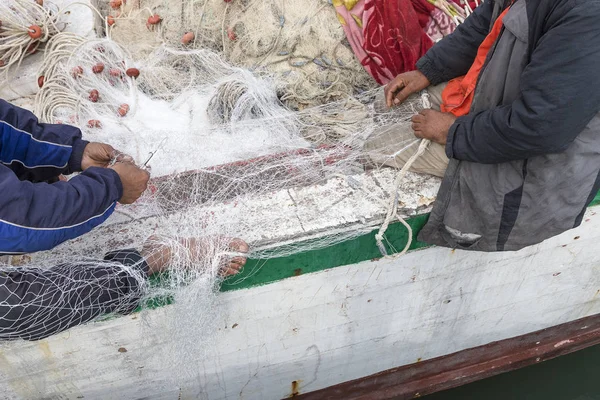 Pescadores são vistos reparando as redes de peixes na praia de Houmt Souk Tunísia — Fotografia de Stock