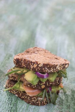 Countrybread avokado, tuzlanmış somon sandviç taze herss yeşil aileninde paintt ahşap tahta arka plan ile. Sağlıklı yeme Tema