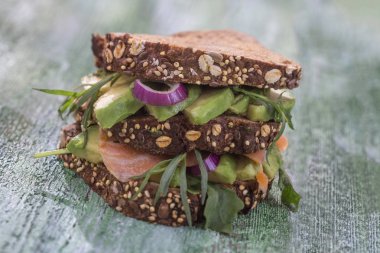 Countrybread avokado, tuzlanmış somon sandviç taze sürüler üzerinde yeşil aileninde paintt ahşap tahta arka plan ile. Sağlıklı yeme Tema