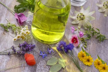 Aroma esans. Üstten Görünüm r şişe renkli taze çiçekler, şifalı otlar çeşitli, arasında kırık mor ahşap masa dağınık.