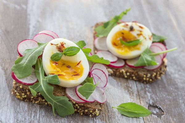 A hearty whole wheat sandwich with arugula, radishes and eggs