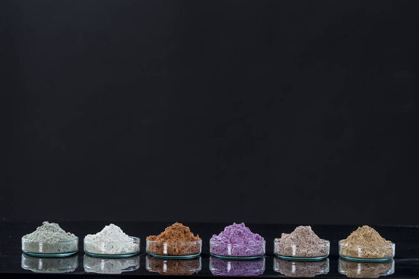 Древние минералы - Выровненная глина из нескольких цветов глины порошок и грязи маска для спа, концепция красоты ocrop на черном фоне
