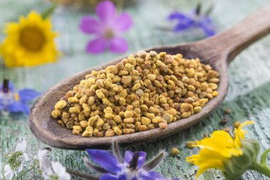 Tahta kaşık polen çiçek tarafından çevrili tablo ile