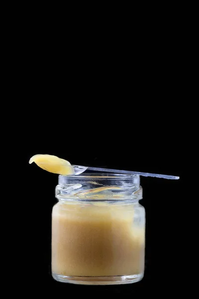 RAW ekologiczne mleczko pszczele w małej butelce z łyżka nosze na czarny — Zdjęcie stockowe