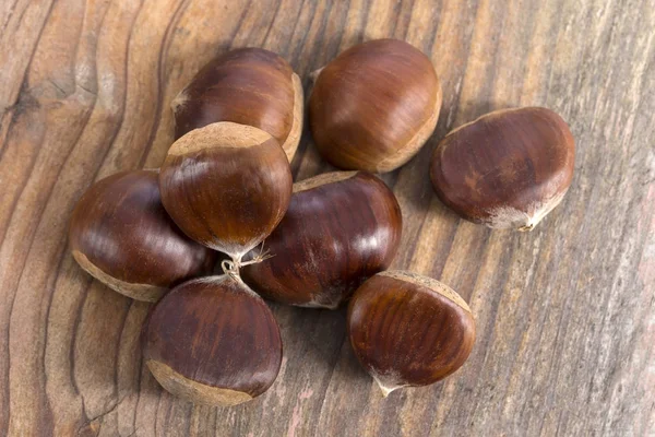 Castañas frescas aisladas en tablón de madera blanquecino — Foto de Stock