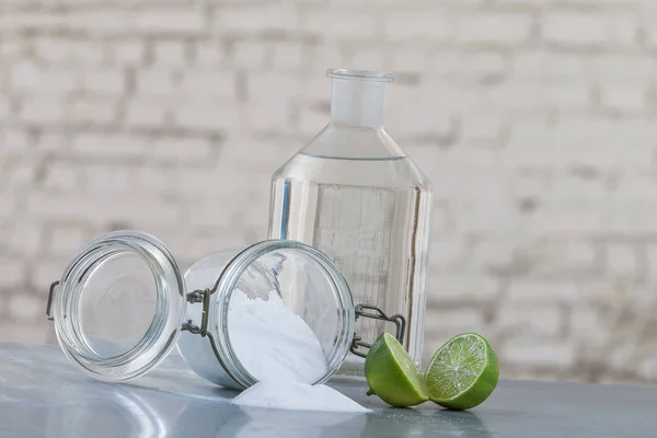 Productos de limpieza naturales, incluidos bicarbonato de sodio, frasco invertido, bicarbonato de sodio, limón, vinagre, sobre una mesa gris sobre fondo gris antiguo — Foto de Stock