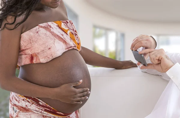 Schöner Mann fotografiert mit Smartphone junge glückliche schwangere Frau im Wohnzimmer — Stockfoto