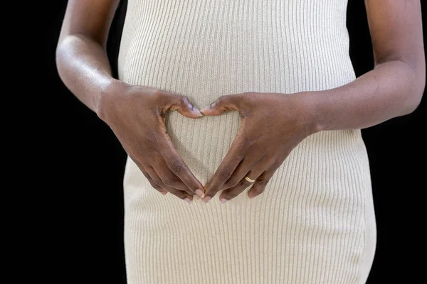 Perut hamil, wanita memegang tangannya dalam bentuk hati pada benjolan bayinya dengan jari-jari, dekat — Stok Foto