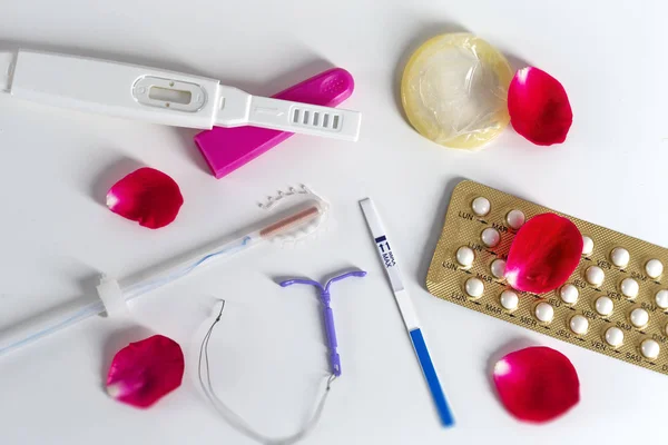 Concept of Birth Control symbol- IUD and contraceptive Pills and Condom with rose petals — Stock Photo, Image