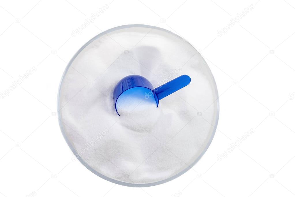 Top view of baking soda bowl with ,blue, spoon on white